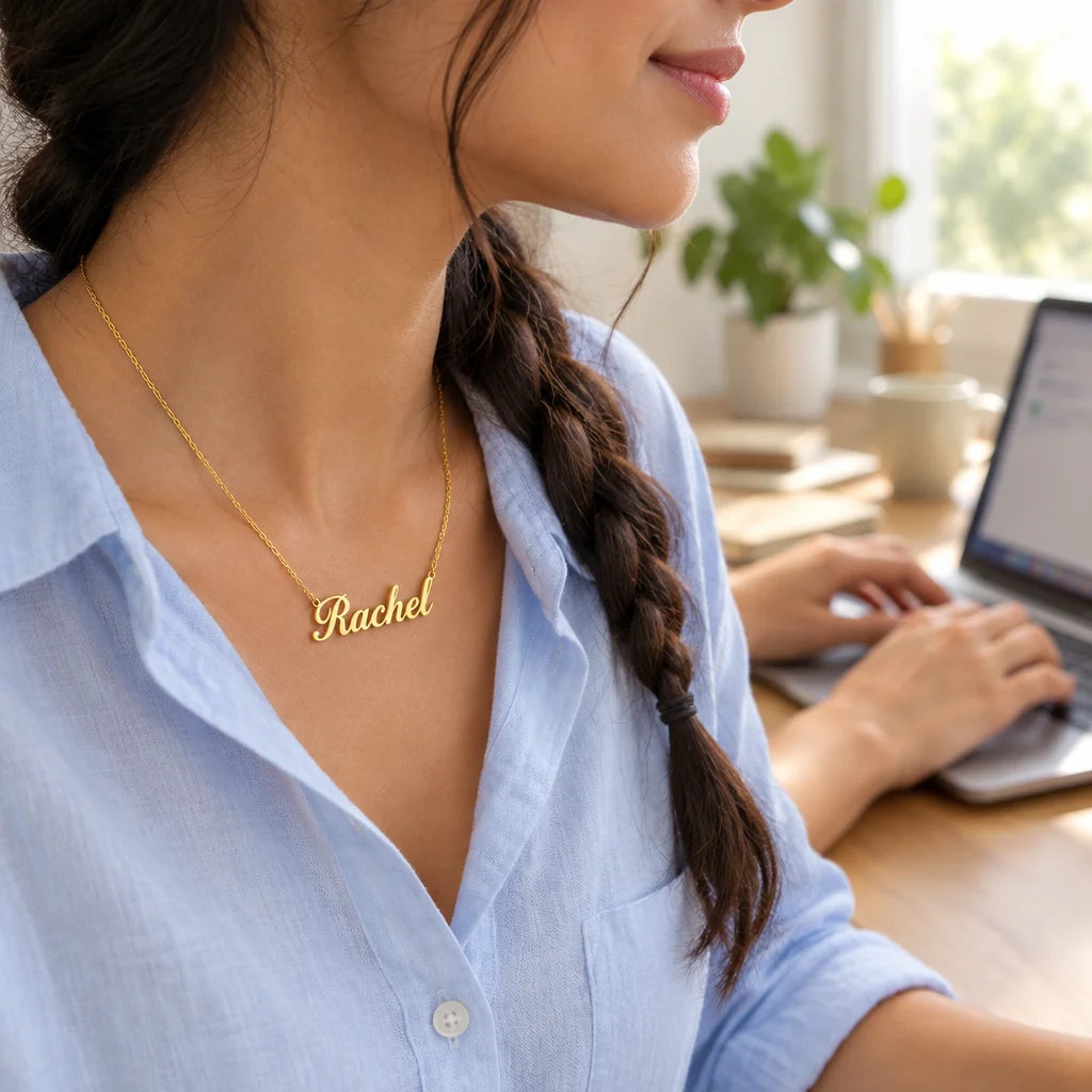 A gold stainless-steel personalized name necklace with a fine chain and cursive pendant, worn close